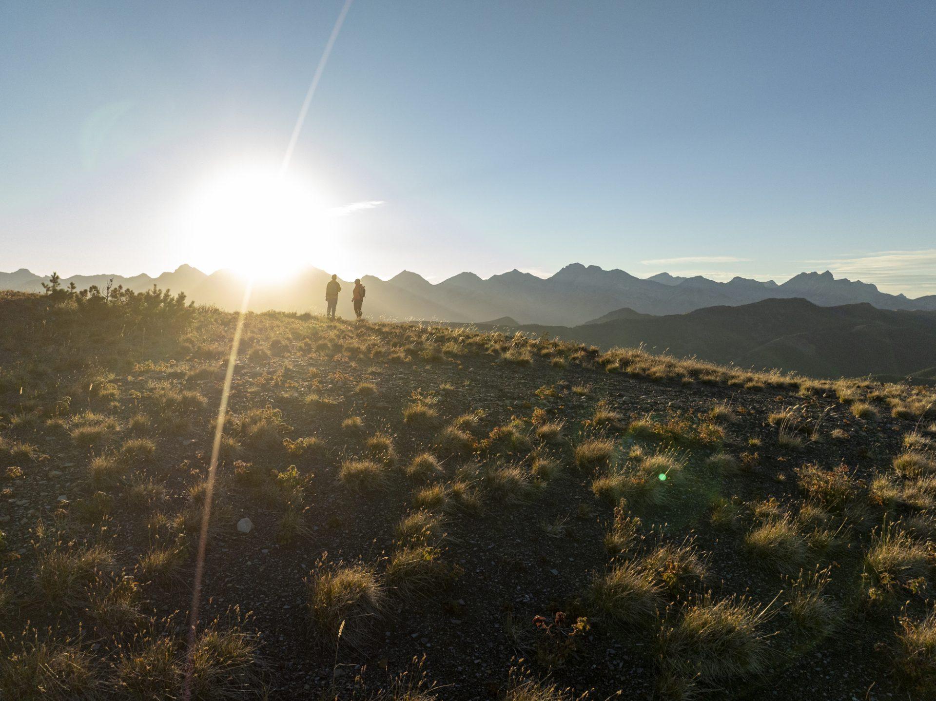 Hikers on golden ridgeline at sunset